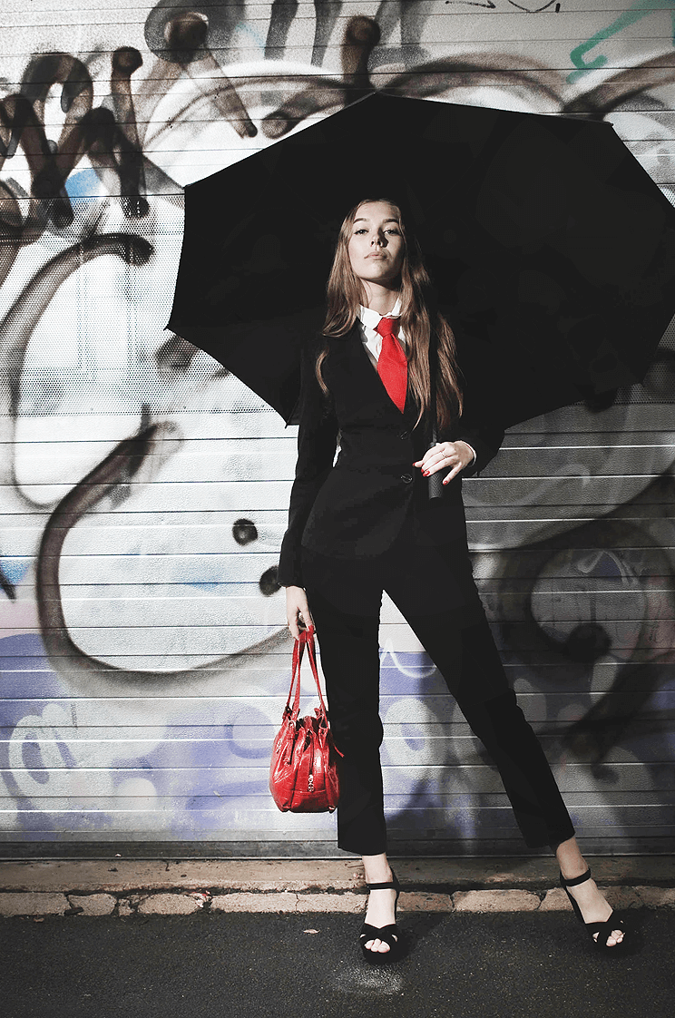 Model fotografering model med stor paraply og rød taske og slips